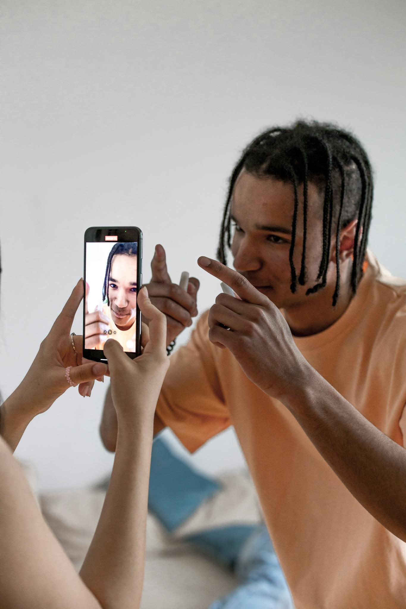 A young adult male creating content with a smartphone indoors for vlogging.